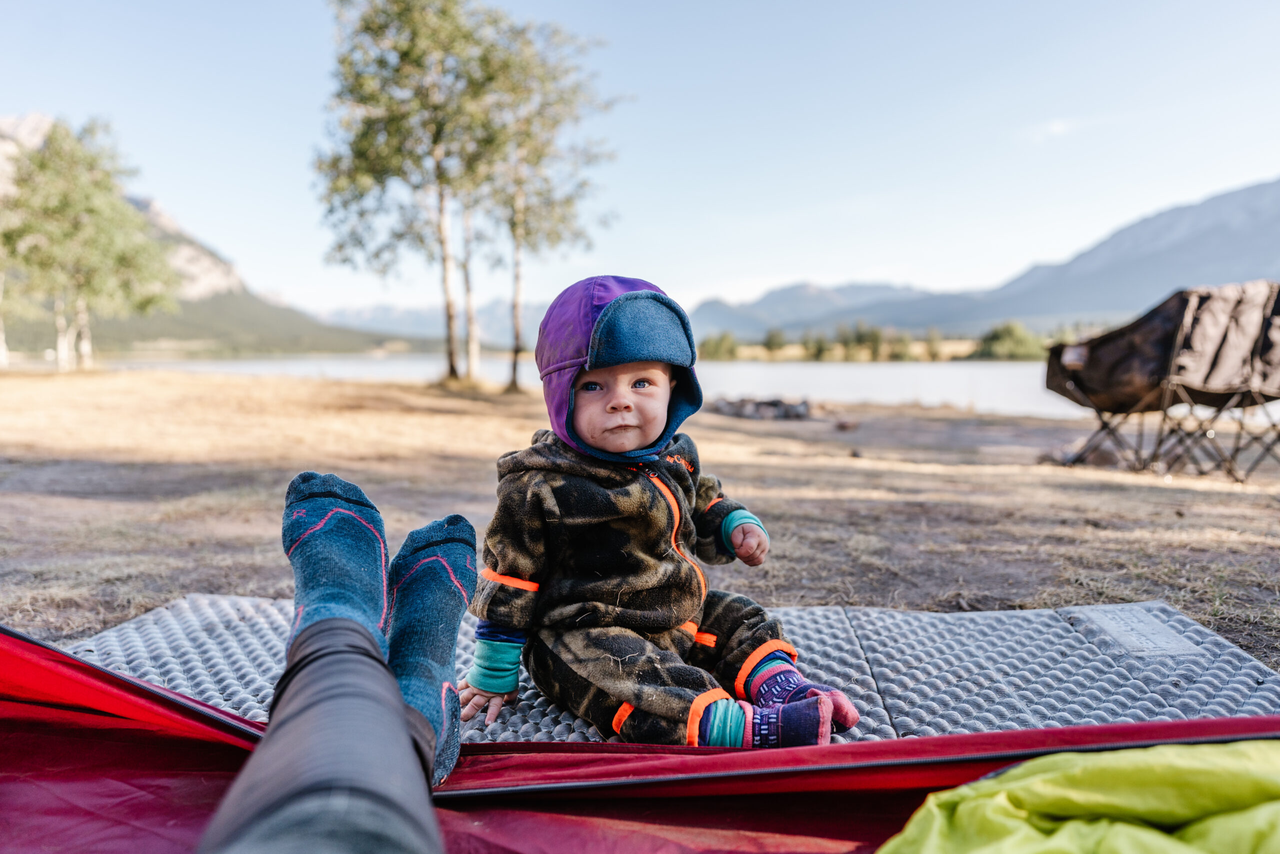 baby sits on thermarest pad while wearing cozy layers while camping in alberta