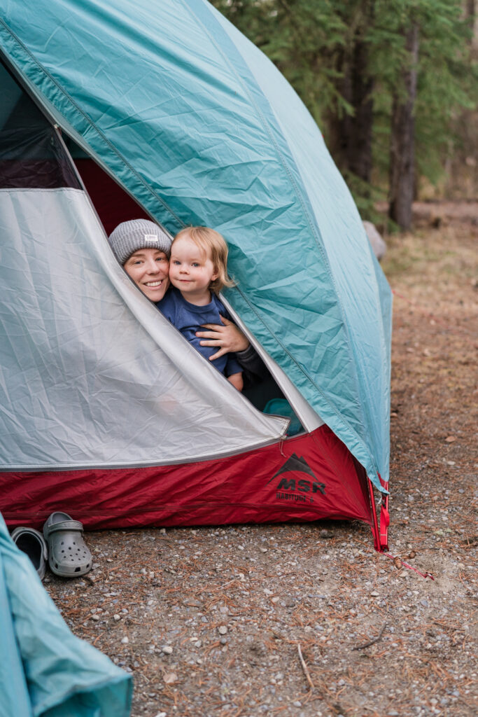mom and toddler peek out of MSR tent and smile while camping